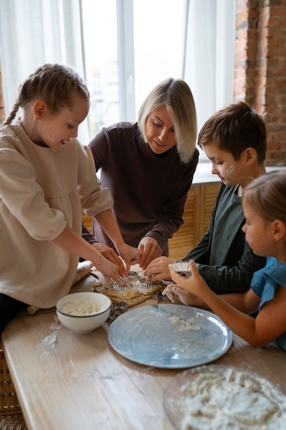 Vista frontal mujer ayudando a los niños a cocinar
