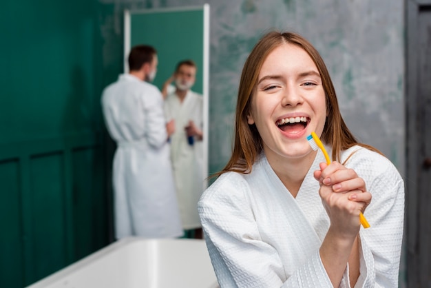 Vista frontal de la mujer en bata de baño cantando en el cepillo de dientes