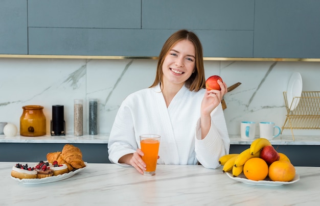 Vista frontal de la mujer en bata de baño con manzana