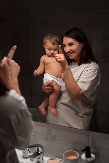 Vista frontal mujer con bebé en el baño.