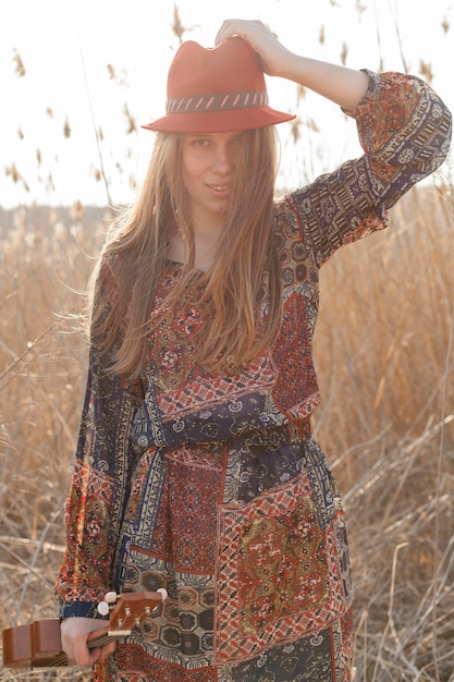 Foto gratuita vista frontal de la mujer bohemia posando en el campo con ukelele