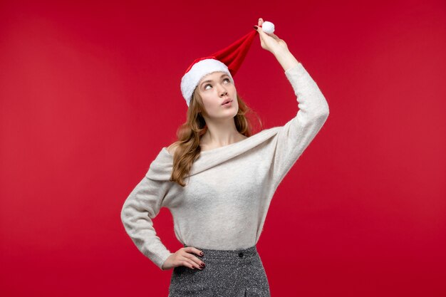 Vista frontal de una mujer bonita jugando con gorra roja sobre rojo