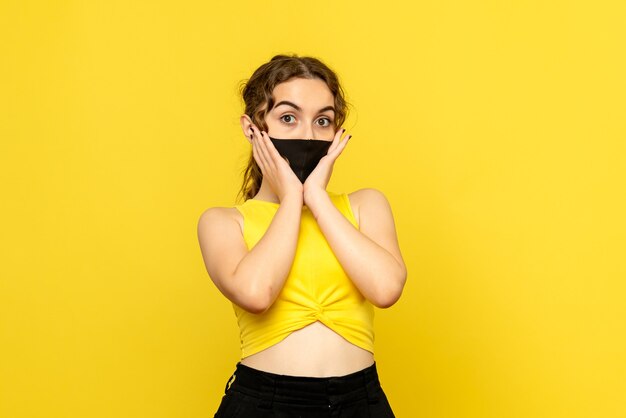 Vista frontal de mujer bonita en máscara en amarillo
