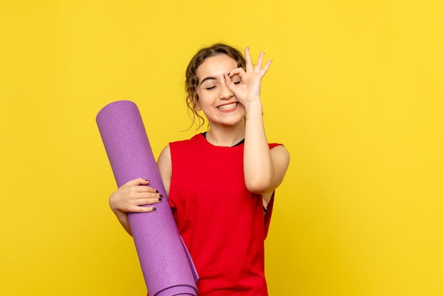 Vista frontal de una mujer bonita sonriendo con alfombra púrpura sobre amarillo