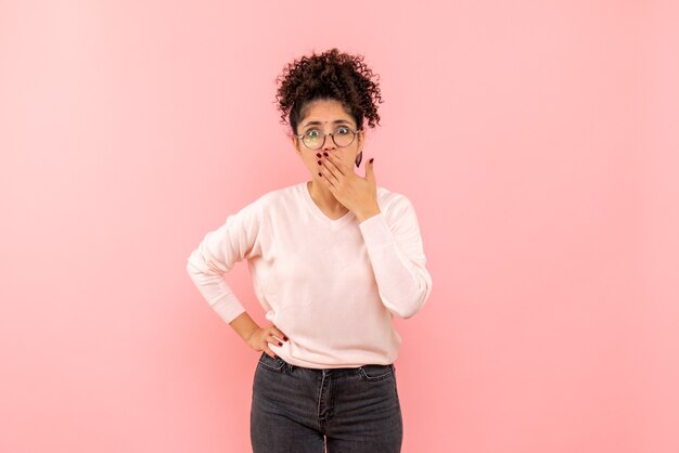 Vista frontal de una mujer bonita sorprendida en la pared rosa