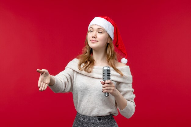 Vista frontal de la mujer bonita sosteniendo el micrófono en rojo