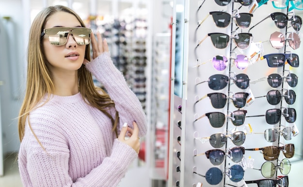 Foto gratuita vista frontal de una mujer bonita en suéter blanco pruebe gafas en tienda profesional en