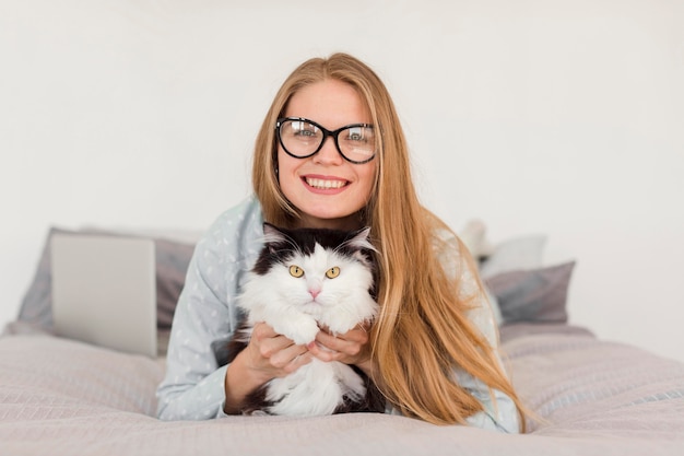 Foto gratuita vista frontal de la mujer en la cama vistiendo pijama con gato y portátil