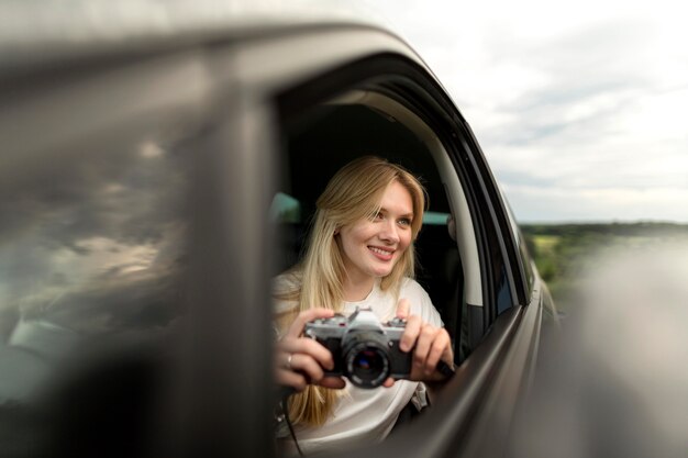 Vista frontal de la mujer con cámara en el coche