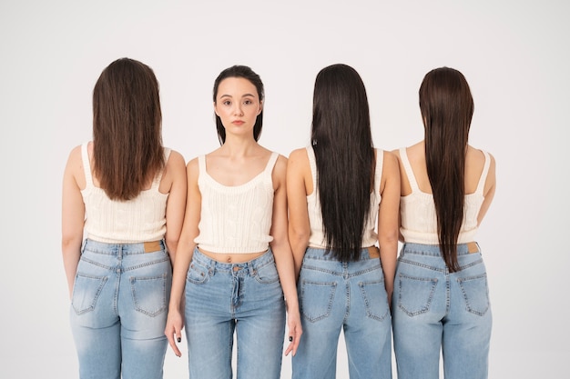 Vista frontal de la mujer en camiseta sin mangas y jeans de pie junto a otras mujeres con la espalda vuelta