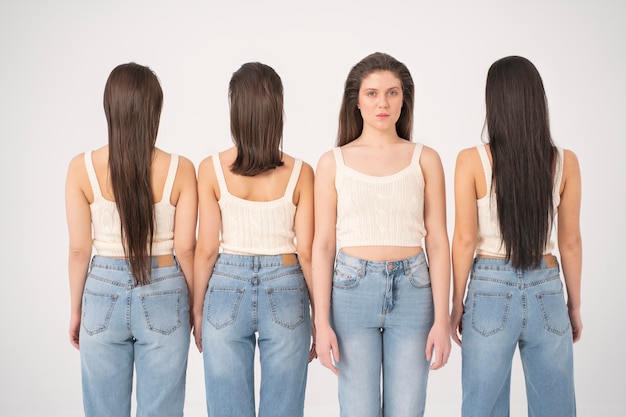 Vista frontal de la mujer en camiseta sin mangas y jeans de pie junto a otras mujeres con la espalda vuelta