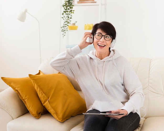 Vista frontal de la mujer en casa con auriculares y tableta