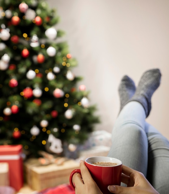 Vista frontal mujer en casa bebiendo té en Navidad