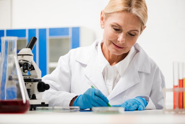 Vista frontal de la mujer científica escribiendo algo en el laboratorio