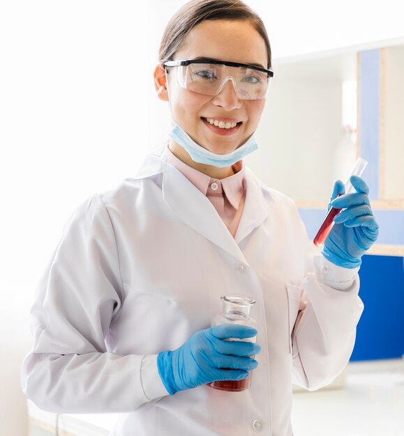 Vista frontal de la mujer científica con guantes quirúrgicos posando en el laboratorio