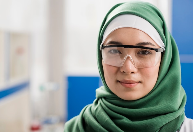 Vista frontal de la mujer científica con hijab posando en el laboratorio