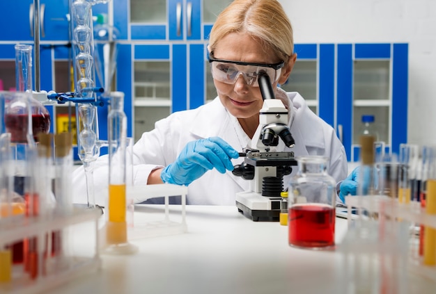 Vista frontal de la mujer científica que trabaja con microscopio en el laboratorio