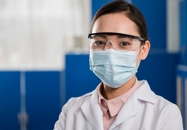 Vista frontal de la mujer científico con máscara médica