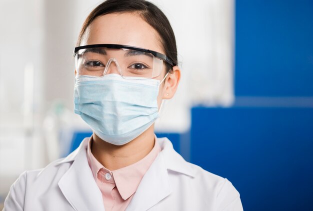 Vista frontal de la mujer científico con máscara médica