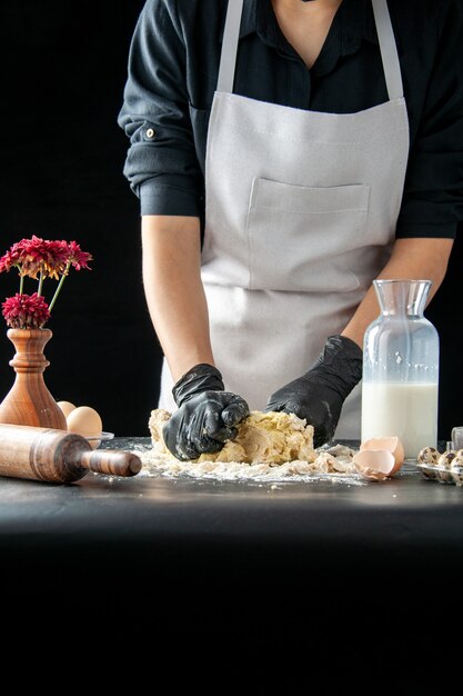 Vista frontal de la mujer cocinera extendiendo la masa en el trabajo oscuro pastel de pastelería panadería cocinar pastel masa de galletas hornear