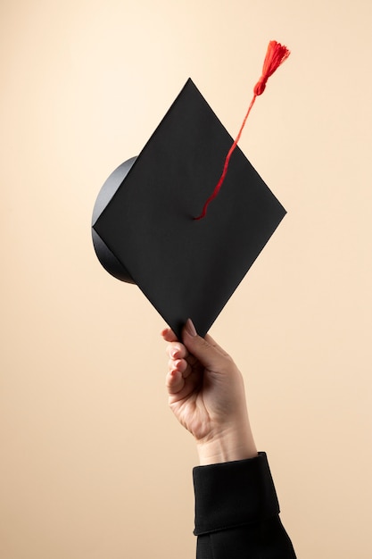 Foto gratuita vista frontal de una mujer cogiendo un gorro de graduación para el día de la educación