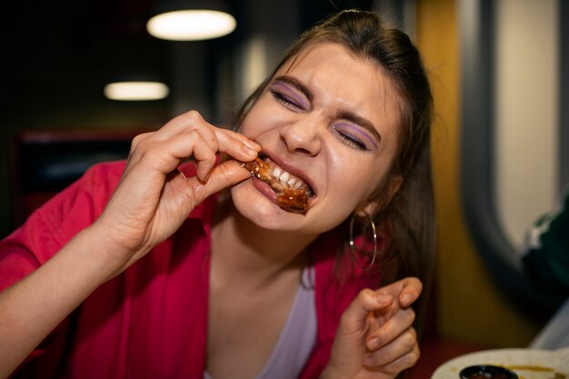 Vista frontal mujer comiendo alitas de pollo