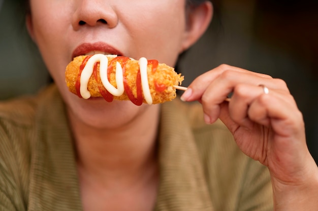 Vista frontal mujer comiendo corn dog