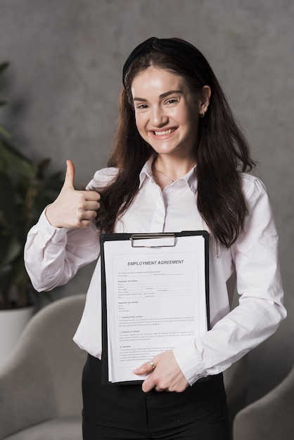 Foto gratuita vista frontal de la mujer con contrato y dando pulgares arriba