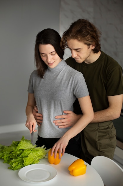 Vista frontal de la mujer cortando verduras con novio