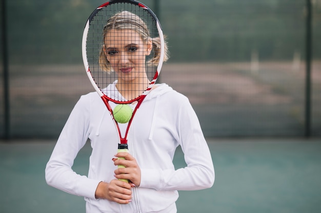 Foto gratuita vista frontal mujer cubriéndose la cara con raqueta de tenis