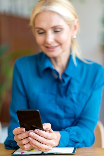 Vista frontal de la mujer desenfocada sosteniendo smartphone mientras trabaja