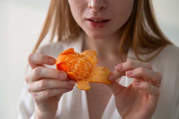 Foto gratuita vista frontal mujer despegando mandarina