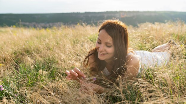 Vista frontal de la mujer disfrutando de la hierba en la naturaleza