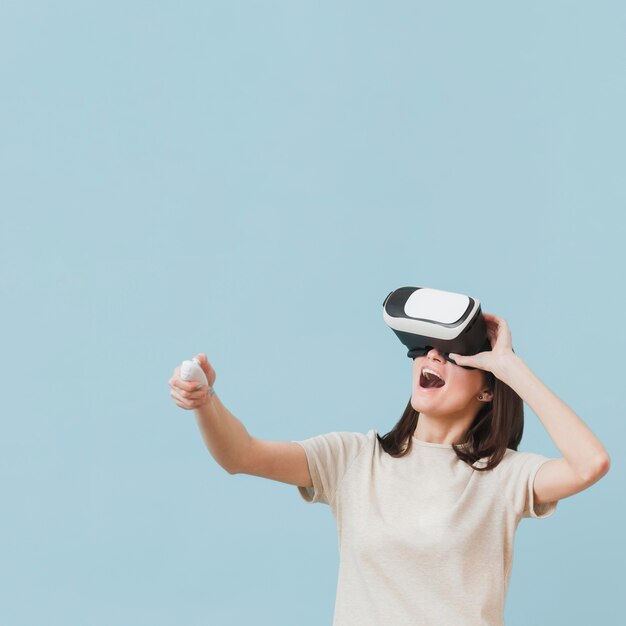 Vista frontal de la mujer disfrutando de su tiempo con casco de realidad virtual