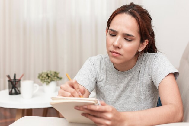 Vista frontal de la mujer escribiendo algo en el cuaderno