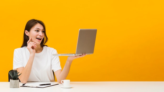 Vista frontal de la mujer en el escritorio disfrutando de lo que ve en su computadora portátil con espacio de copia