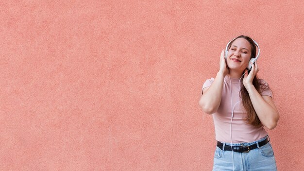 Vista frontal de la mujer escuchando música en auriculares con espacio de copia