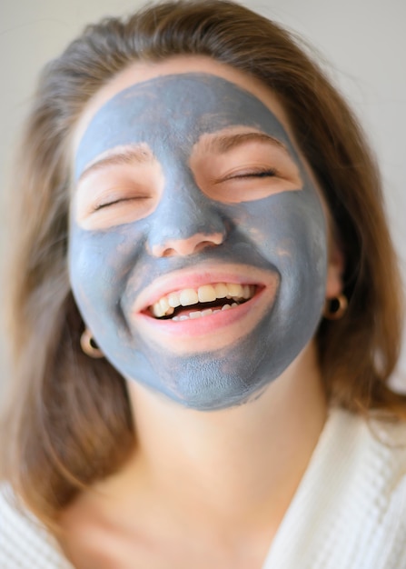 Foto gratuita vista frontal de una mujer feliz con mascarilla relajante en casa