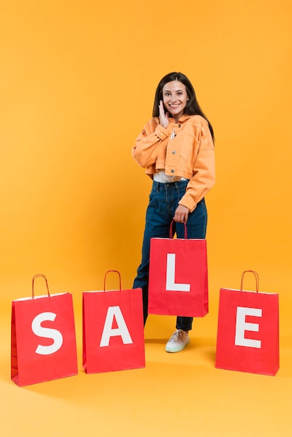 Vista frontal de la mujer feliz posando con bolsas de compra venta