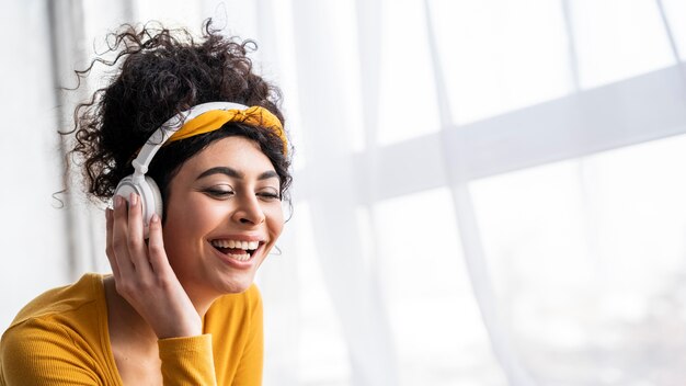 Vista frontal de la mujer feliz riendo y escuchando música en auriculares con espacio de copia