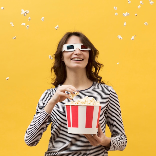 Vista frontal mujer con gafas 3d sosteniendo un cubo con palomitas de maíz