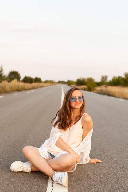 Vista frontal de la mujer con gafas de sol posando en la carretera