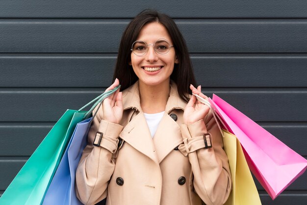 Foto gratuita vista frontal de la mujer con gafas sosteniendo un montón de bolsas de la compra.