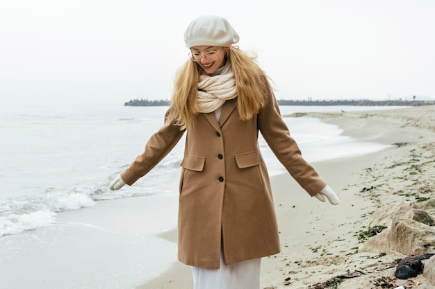 Foto gratuita vista frontal de la mujer con guantes en la playa durante el invierno