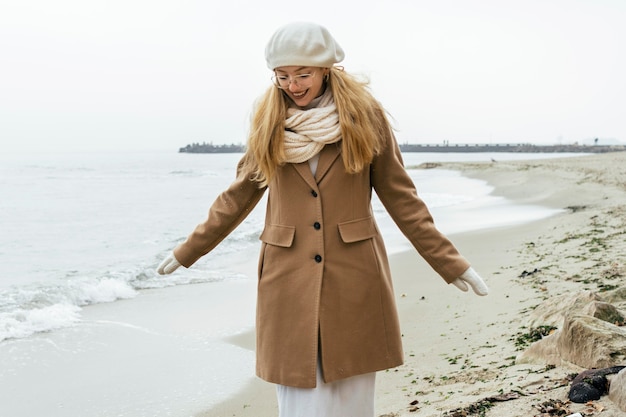 Vista frontal de la mujer con guantes en la playa durante el invierno