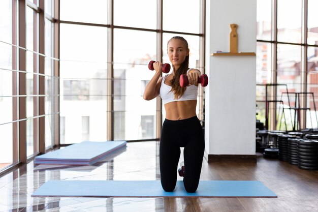 Vista frontal de la mujer haciendo entrenamiento con pesas