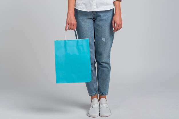 Vista frontal de la mujer en jeans con bolsa de compras