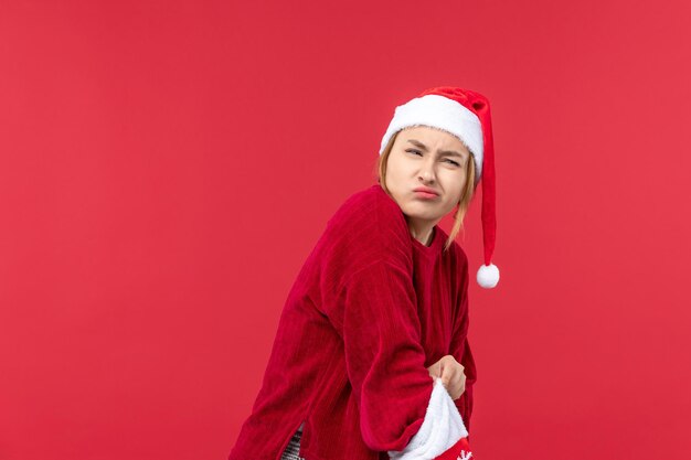 Vista frontal mujer joven abriendo gran calcetín de navidad en el escritorio rojo rojo de vacaciones de navidad