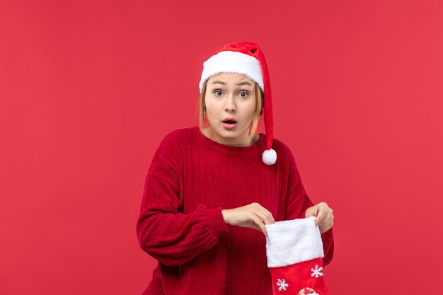 Vista frontal mujer joven abriendo gran calcetín navideño, vacaciones navideñas rojo