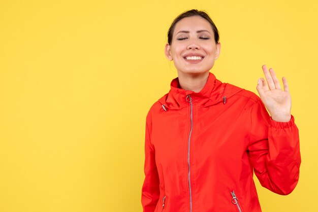 Vista frontal mujer joven en abrigo rojo sobre fondo amarillo